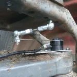 Traktor első tengelyére szerelt kerékszögszenzor összekötő rúddal