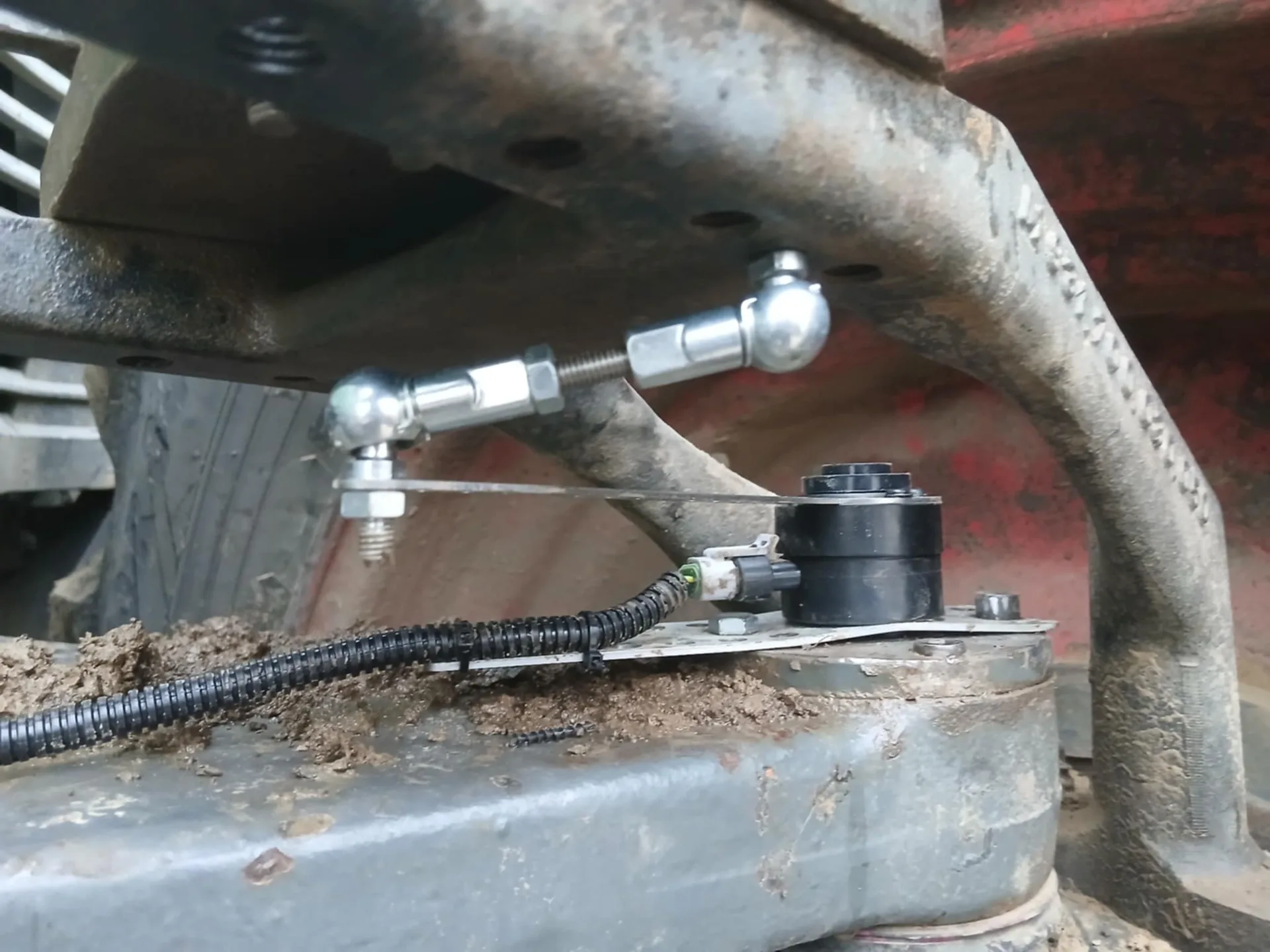Traktor első tengelyére szerelt kerékszögszenzor összekötő rúddal